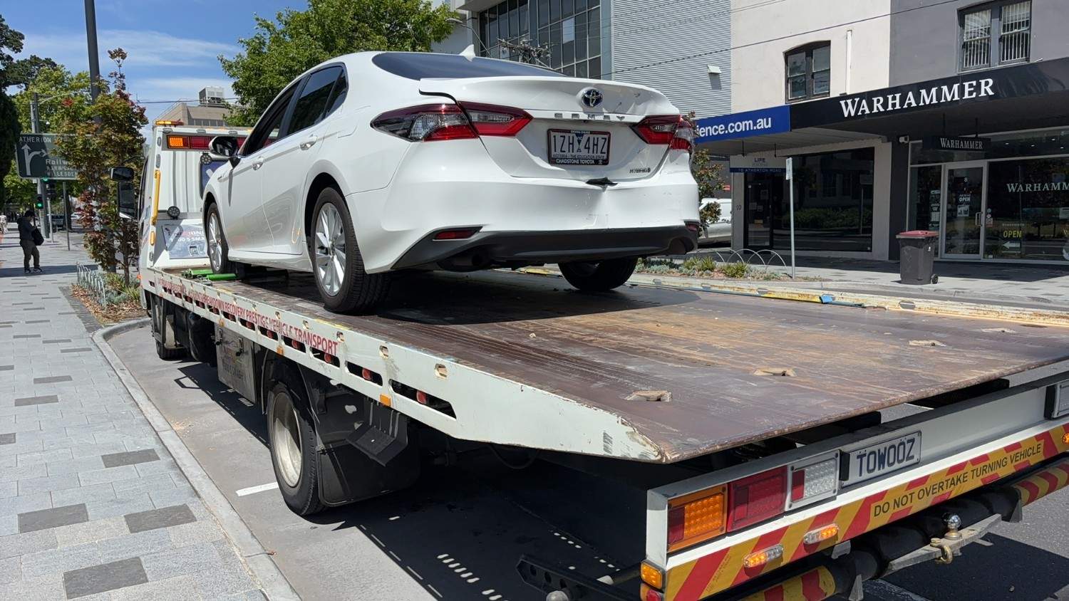 car towing Melbourne flatbed truck transporting a white sedan after an accident in the city