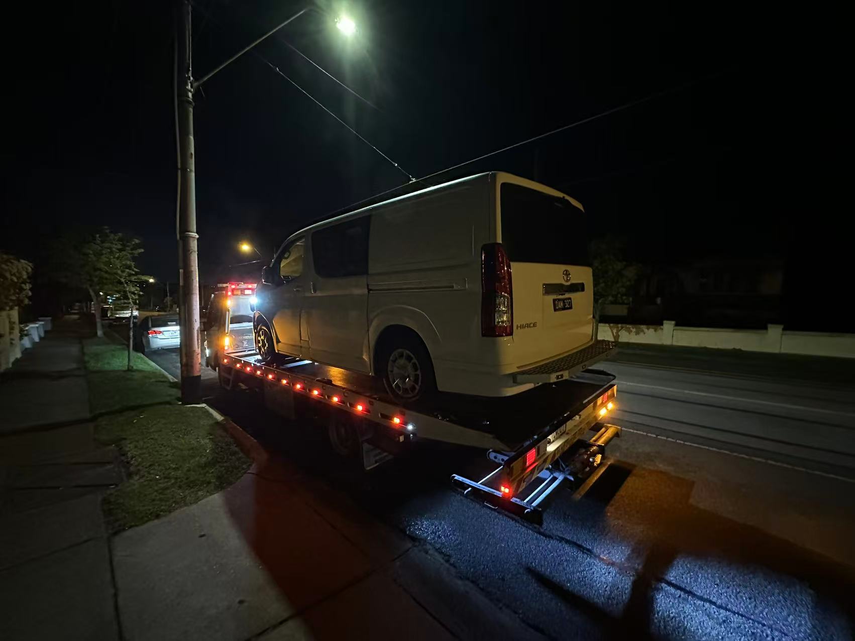 Tow truck Melbourne assisting a white van at night on a quiet Melbourne street