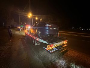 Car secured on flatbed tow truck under streetlights during night towing operation in Melbourne