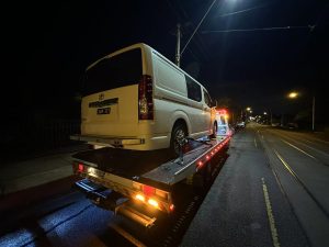Melbourne tow truck carrying a white commercial van under street lights