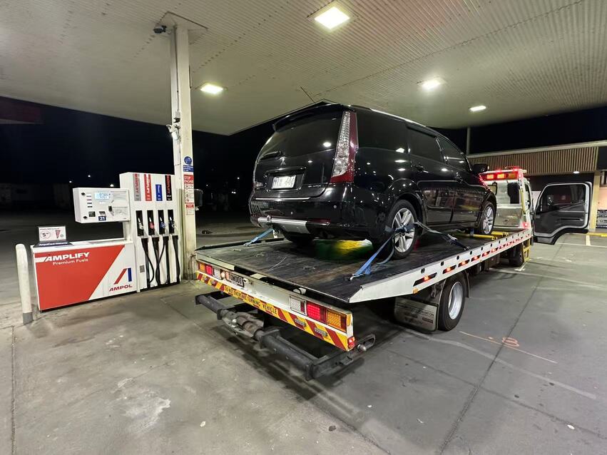 Car towing Melbourne – black SUV loaded on tow truck at Ampol fuel station