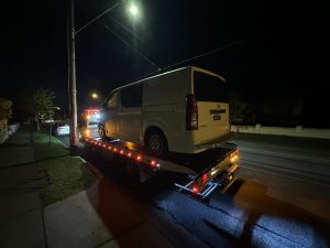 24 hour tow truck performing emergency towing for white van at night in Melbourne