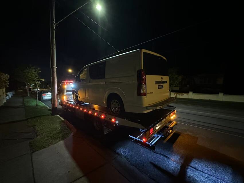 24 hour tow truck performing emergency towing for white van at night in Melbourne