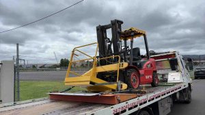 Industrial forklift secured on flatbed tow truck for transport