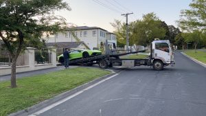 Maningham Towing tow truck Melbourne loading a green sports car for accident towing service in a residential street