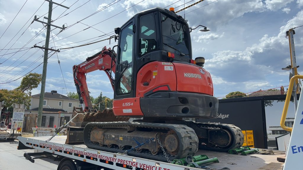 Excavator secured on a flatbed tow truck for heavy equipment towing in Melbourne