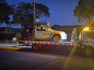 Tow truck Melbourne service moving a work ute at night with emergency towing lights