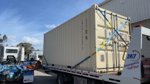 Tow truck transporting a shipping container for heavy vehicle recovery in Melbourne