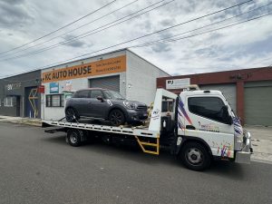 Flatbed tow truck transporting a Mini Countryman to an auto service centre in Melbourne