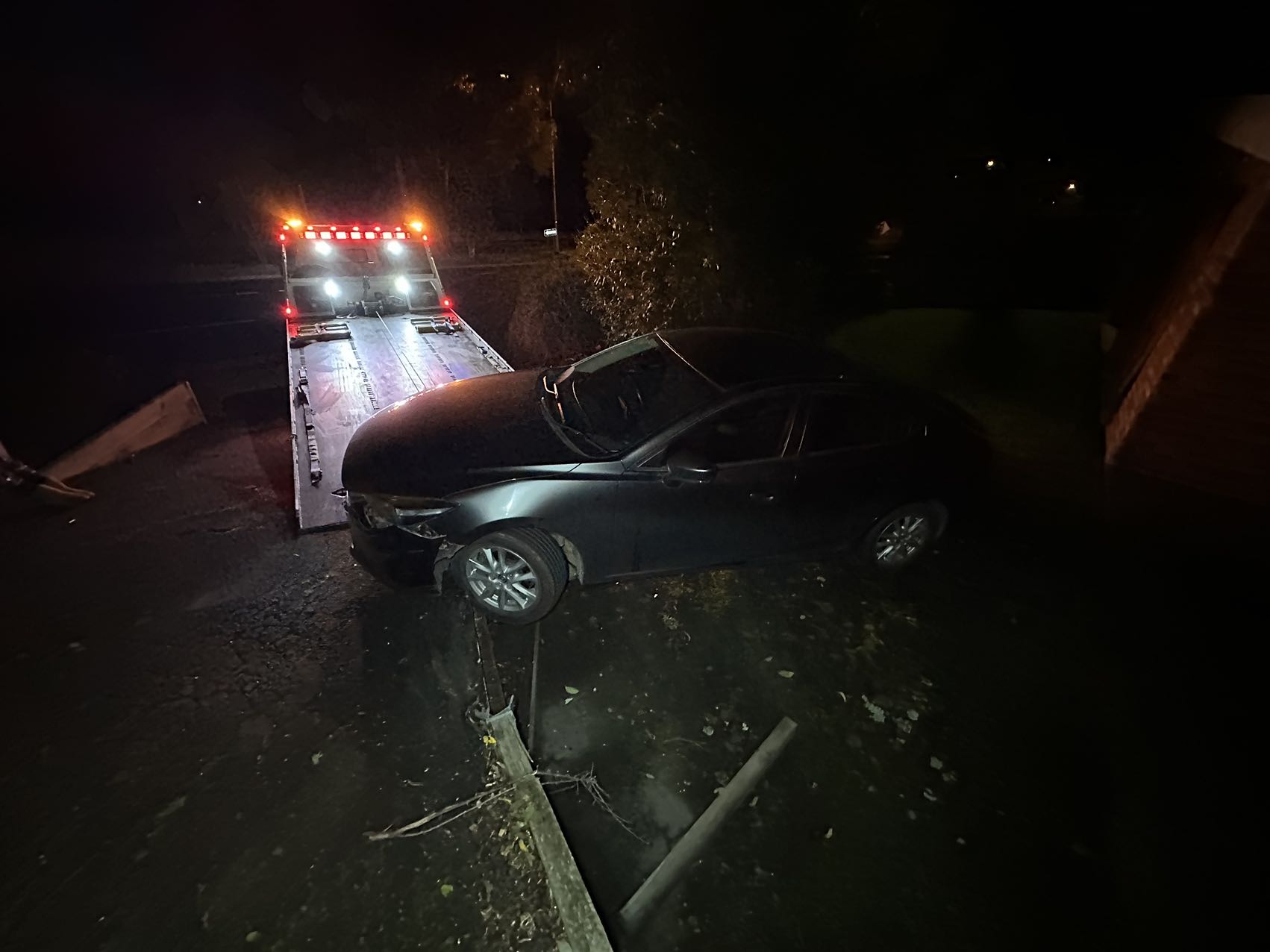 Damaged car being recovered by a tow truck at night